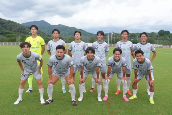 グラウンドに並ぶ飛鳥FCの選手11人の集合写真