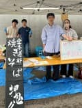 「焼きそば 押忍」と書かれた黒い看板と、テントの下の屋台に立つ空手道部の部員の写真