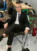 スーツ姿で椅子に座る眼鏡の男性
