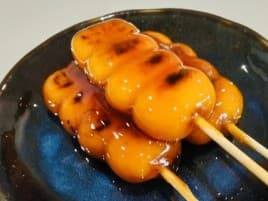 皿にのった、たれのかかったみたらし団子の串