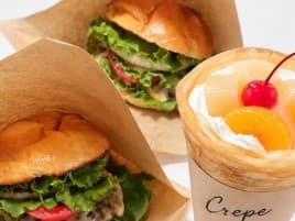 紙に包まれたハンバーガー2つと、果物とクリームのクレープ
